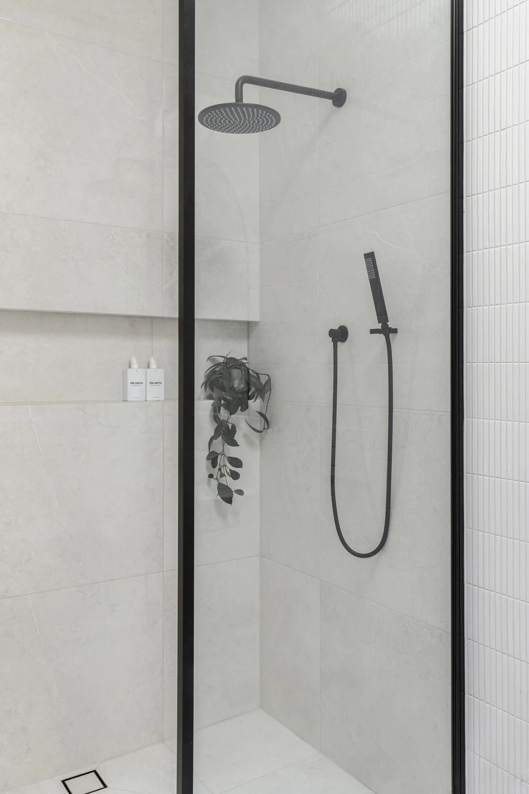 Matte Black shower tapware paired with soft grey tiles and a shower shelf