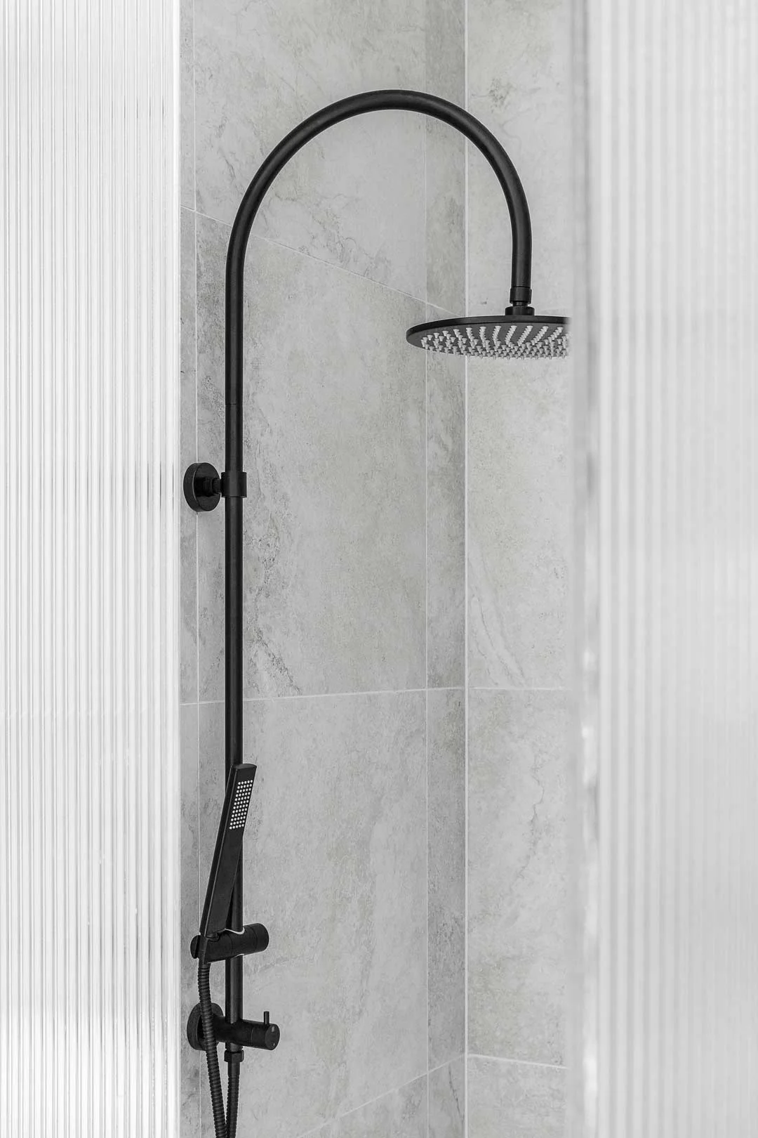 A sleek matte black shower set and fluted shower glass