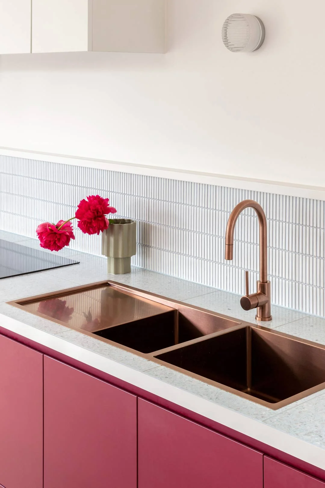 A statement sink in brushed copper with a drip tray and matching mixer in a bright colourful kitchen