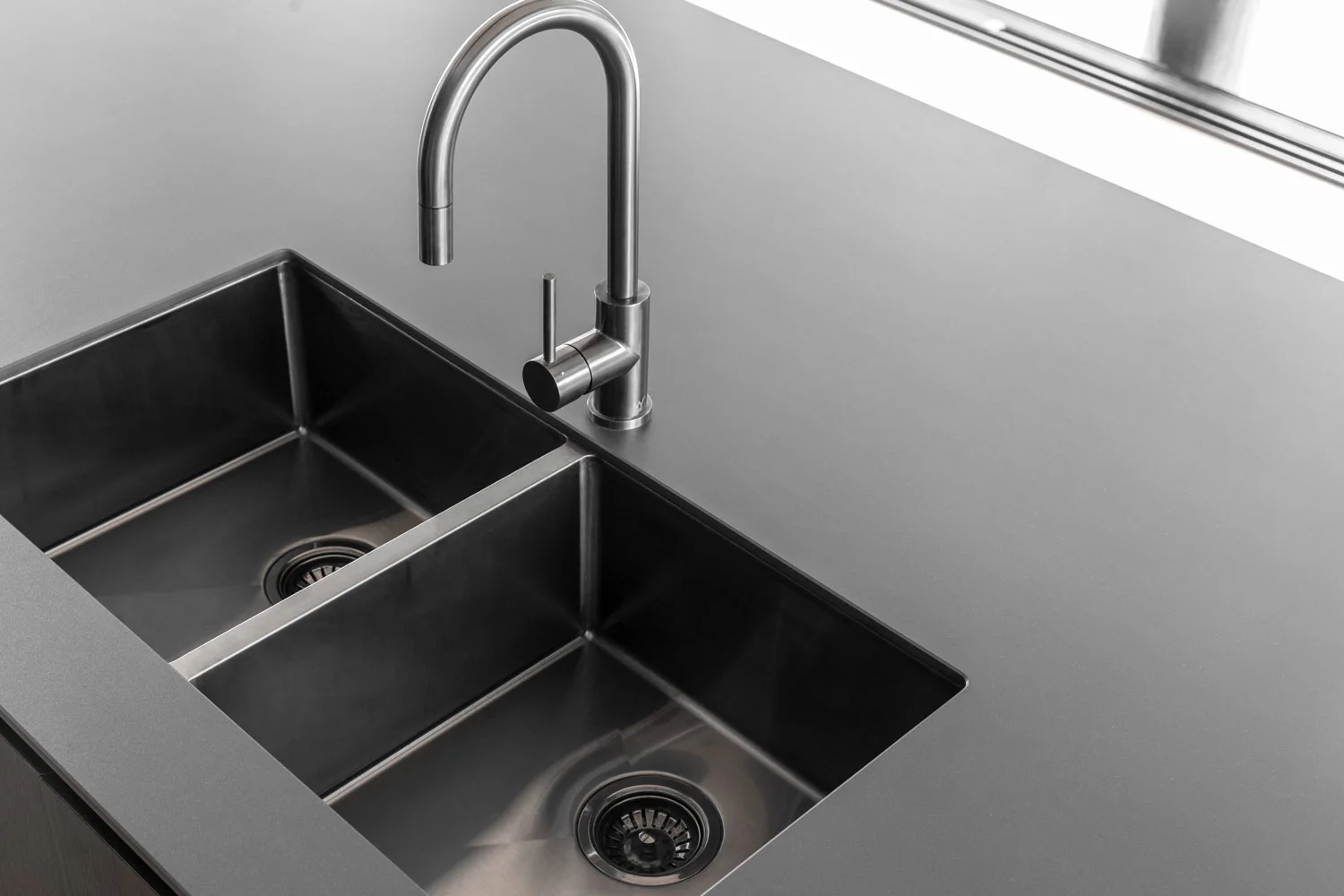 Brushed gunmetal double undermount sink with mixer in a dark kitchen