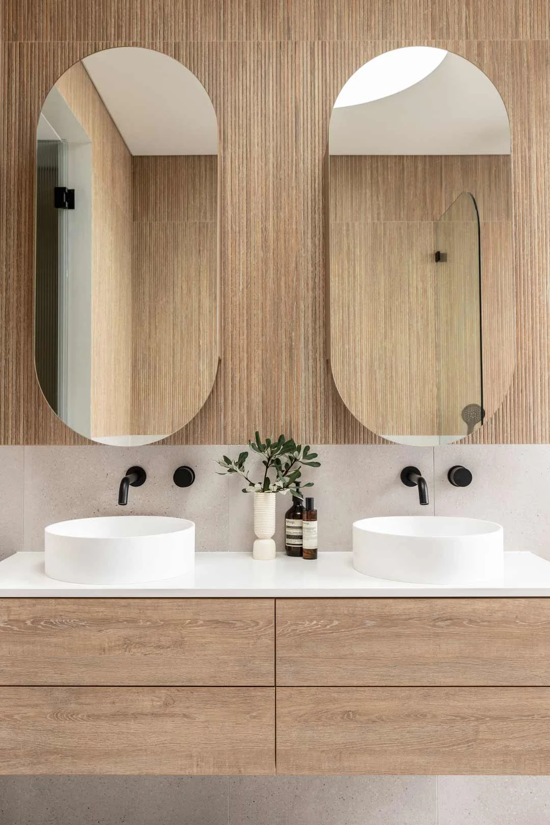 Matte black tapware paired with round white basins on a double timber vanity in this modern home