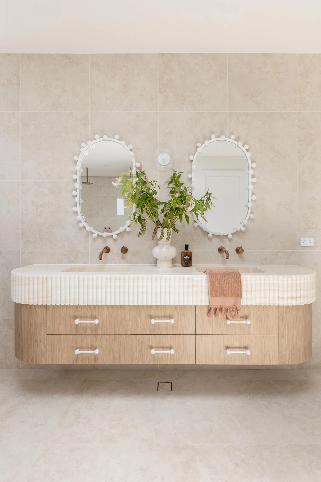 creamy onyx scalloped stone double basin vanity in neutral bathroom